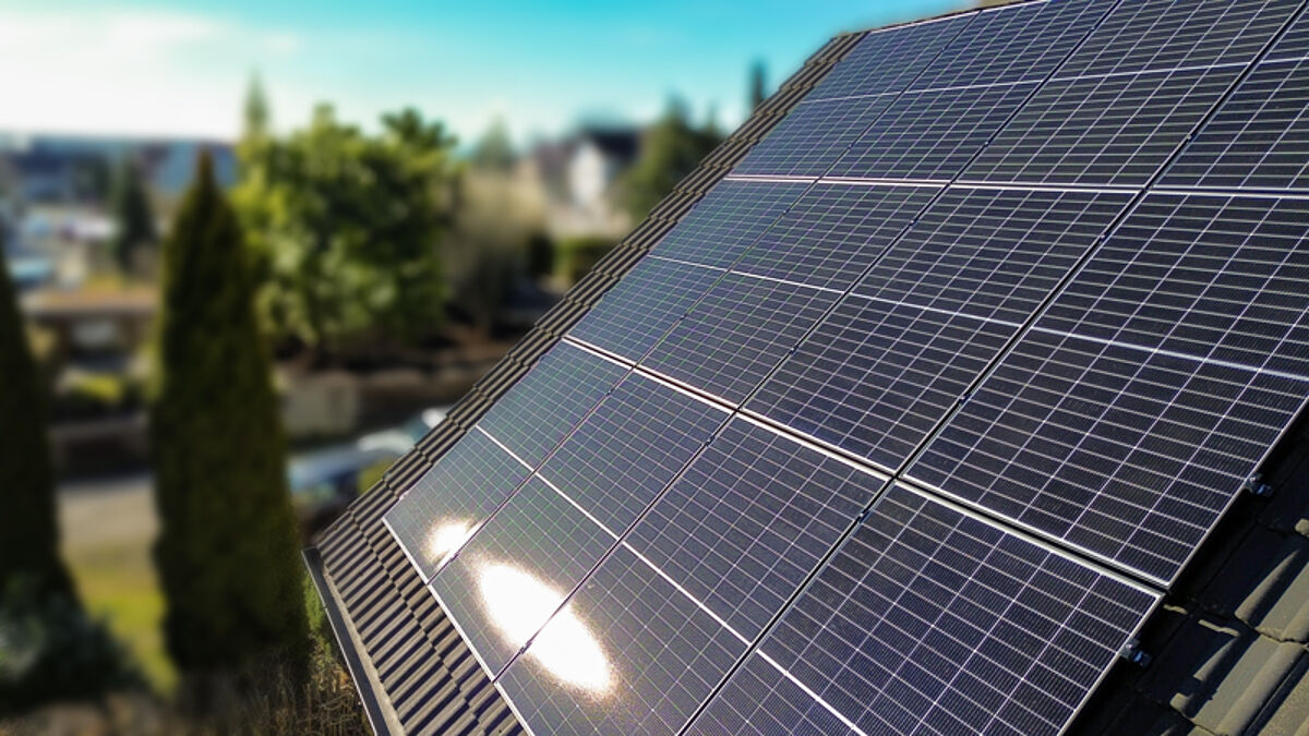 Photovoltaikmodule auf dem Dach eines Gebäudes erzeugen Strom aus Sonnenenergie.